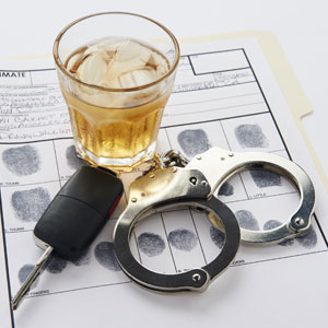 Glass of alcohol, car key, and handcuffs on fingerprint sheet, symbolizing DWI Conviction - Law Office of Ira Z. Miller