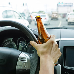 Hand holding a beer bottle while driving, symbolizing DWI charges in Texas - Law Office of Ira Z. Miller