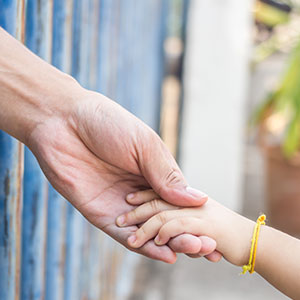 Adult hand holding a child's hand, representing child visitation order in Texas - Law Office of Ira Z. Mill