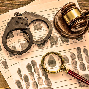 Handcuffs, gavel, fingerprint sheets, and magnifying glass symbolizing Misdemeanors - Law Office of Ira Z. Miller