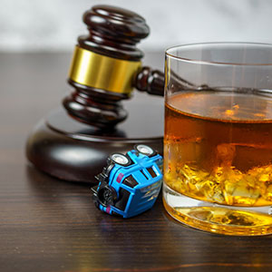 Judge's gavel, whiskey glass, and toy car, symbolizing elements of a DWI case - Law Office of Ira Z. Mill