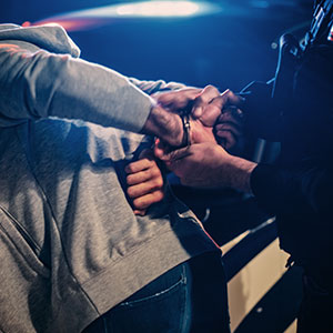 Police officer handcuffing a person during a DWI arrest - Law Office of Ira Z. Miller